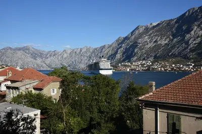 a cruise ship in a body of water with mountains at Apartment Lima in Kotor