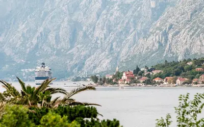 a cruise ship on the water with mountains in the background at Apartment Lima in Kotor