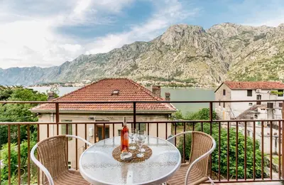a table and chairs on a balcony with mountains at Apartment Lima in Kotor