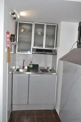 a small kitchen with white cabinets and a sink at Tip top downtown in Podgorica
