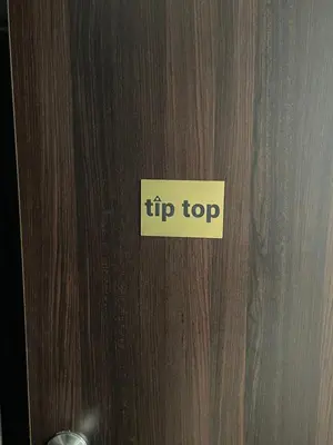 a sign that says tip top on a wooden door at Tip top downtown in Podgorica
