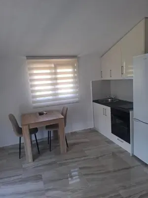 a small kitchen with a wooden table and a window at Apartman Andjela 3 in Lastva