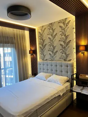 a bedroom with a large white bed with a wall at Montenegro Prestige Suite in Podgorica