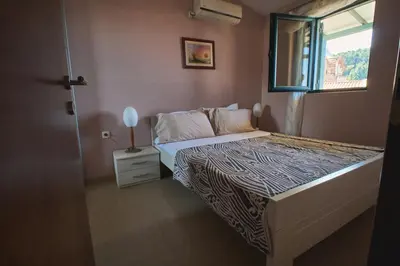 a small bedroom with a bed and a window at Apartman Sveti Stefan in Sveti Stefan