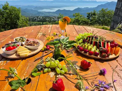 a wooden table topped with plates of food and fruit at Castio del Monte Winery & Resort in Petrovac na Moru