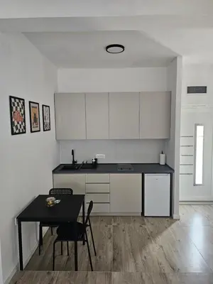 a kitchen with white cabinets and a table with chairs at Cloud 9 Apartment in Lajkovići