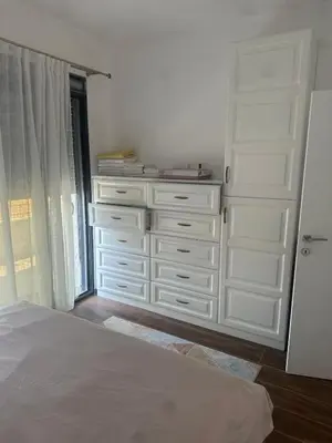 a bedroom with white drawers and a white bed at Ars Dobra Voda in Dobra Voda