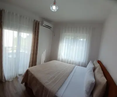 a bedroom with a bed and two windows at L&D Apartments in Ulcinj