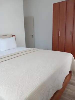 a bedroom with a white bed with a wooden cabinet at L&D Apartments in Ulcinj