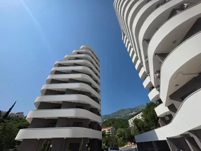 a tall white building next to another building at Laurel apartment in Kravlja