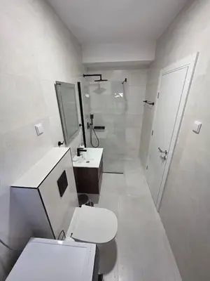 a white bathroom with a toilet and a sink at Laurel apartment in Kravlja