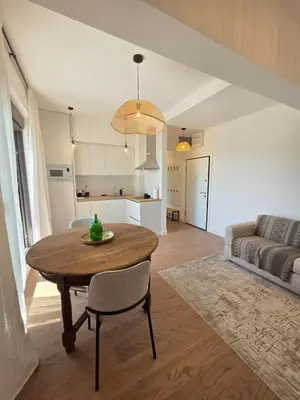 a living room with a wooden table and a kitchen at Laurel apartment in Kravlja