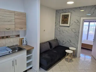 a living room with a black couch and a kitchen at Aparments Plaza in Velika Plaža