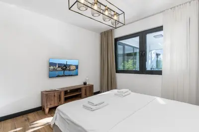 a white bedroom with a bed and a window at Olive Apartment in Sveti Stefan