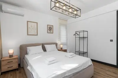 a bedroom with a large white bed and a chandelier at Olive Apartment in Sveti Stefan