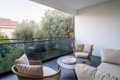 a balcony with chairs and a table and a large window at Olive Apartment in Sveti Stefan
