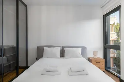 a bedroom with a large white bed with a window at Olive Apartment in Sveti Stefan