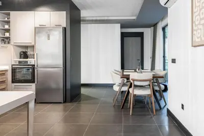 a kitchen with a table and a stainless steel refrigerator at Olive Apartment in Sveti Stefan