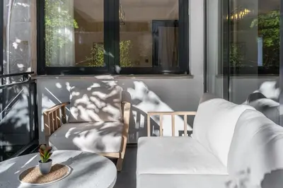 a balcony with two chairs and a table and windows at Olive Apartment in Sveti Stefan