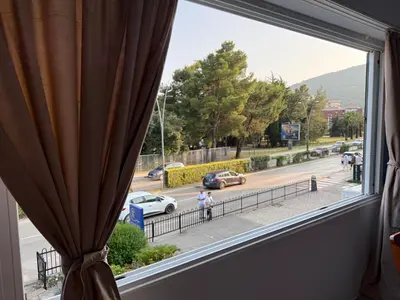 a window with a view of a street with cars at Emines apartman Budva in Budva