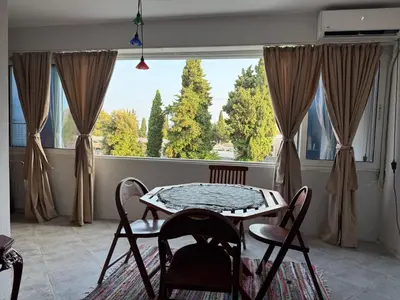 a dining room with a table and chairs and a large window at Emines apartman Budva in Budva