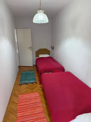 two beds in a room with red sheets at Emines apartman Budva in Budva