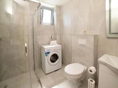 a bathroom with a toilet and a washing machine at Nikola apartmani in Ulcinj
