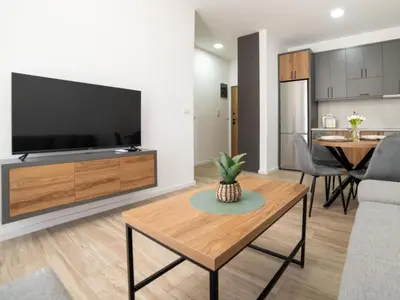 a living room with a large television and a table at Nikola apartmani in Ulcinj