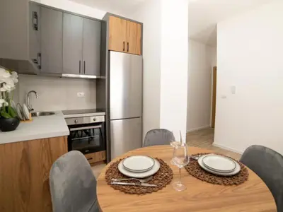 a kitchen with a wooden table with chairs and a dining room at Nikola apartmani in Ulcinj