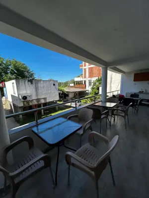 a balcony with tables and chairs and a large window at Apartmani Musić in Ulcinj