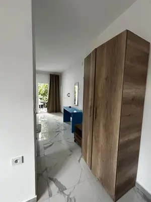 a large wooden cabinet in a room with a blue table at Apartmani Musić in Ulcinj