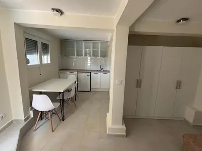 a kitchen with white cabinets and a table and chairs at studio Oliva home in Utjeha