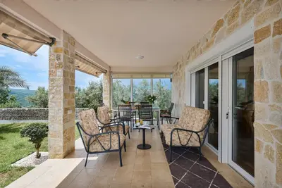 a patio with chairs and a table and glass doors at Villa Oaza with Outdoor Pool in Kotor