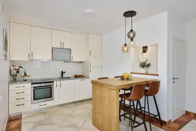 a kitchen with white cabinets and a wooden table at Villa Oaza with Outdoor Pool in Kotor