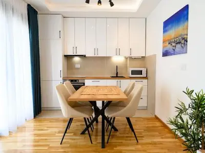 a kitchen with a wooden table and white cabinets at Apartman Adriatico 10 in Bar, Susanj