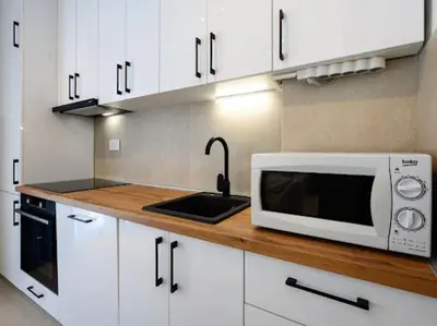 a kitchen with white cabinets and a microwave on a counter at Apartman Adriatico 10 in Bar, Susanj