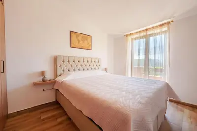a white bedroom with a large bed and a window at Big Hill Apartment 2 in Kotor