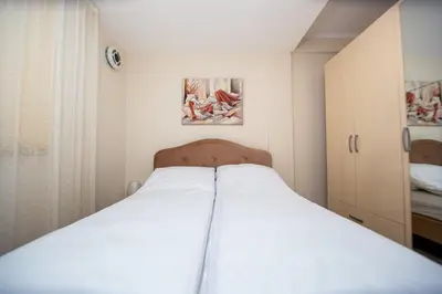 a white bed in a small room with paintings on the wall at KlubNika in Budva