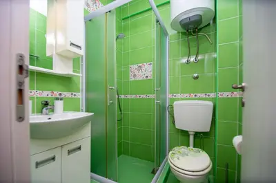 a green bathroom with a toilet and a sink at KlubNika in Budva