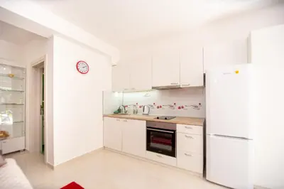 a kitchen with white cabinets and a refrigerator at KlubNika in Budva