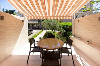 a patio with a table and chairs under awning at KlubNika in Budva