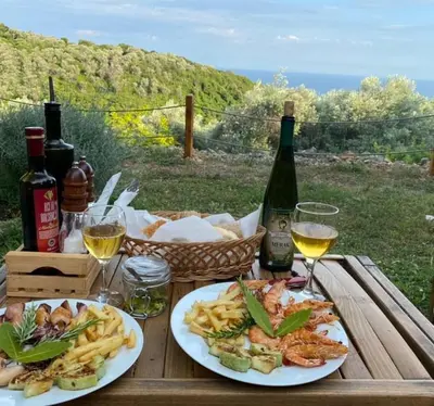 a wooden table with two plates of food and wine at Villa Baccarat in Ulcinj