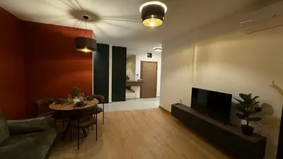 a living room with a couch and a table and a television at Becici Green Oasis Apartment - Nature & Comfort in Becici