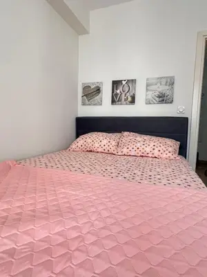a bed with a pink comforter in a bedroom at Ilirija Budva Center Sea Style in Budva