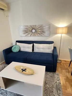 a blue couch in a living room with a table at Ilirija Budva Center Sea Style in Budva