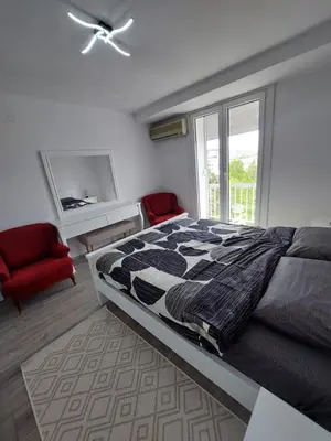 a bedroom with a large bed and a red chair at Golden view apartman in Bar