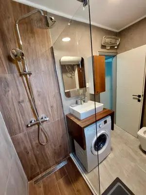 a bathroom with a shower and a sink and a washing machine at Golden view apartman in Bar