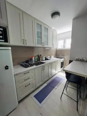 a kitchen with white cabinets and a sink at Golden view apartman in Bar