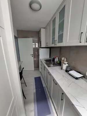 a kitchen with white cabinets and a sink at Golden view apartman in Bar