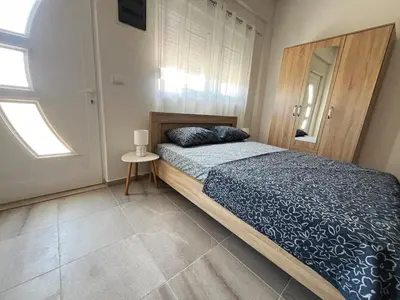 a bedroom with a bed with a blue comforter and a window at Vaidas place in Ulcinj
